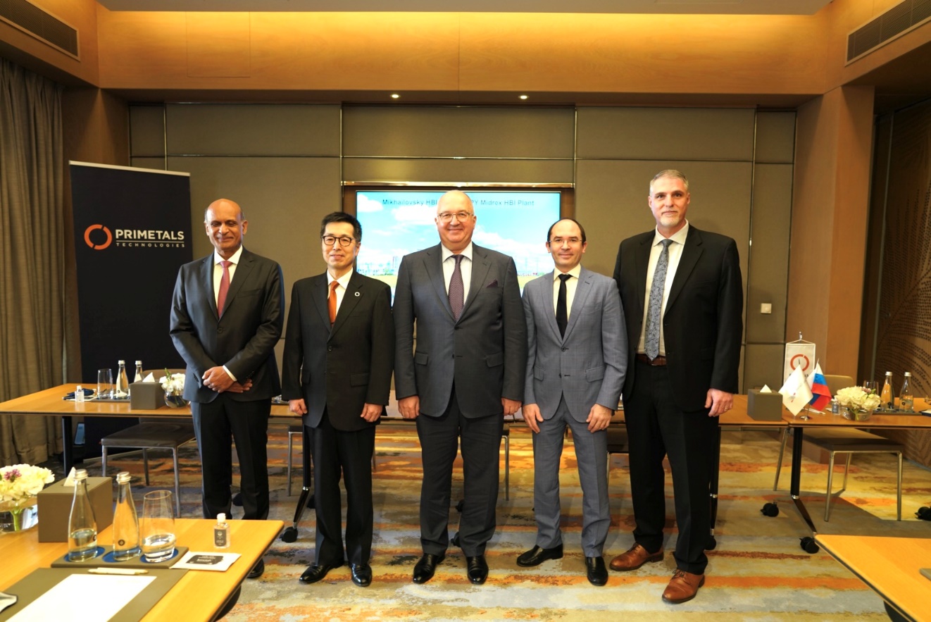 five men in suits standing in conference room